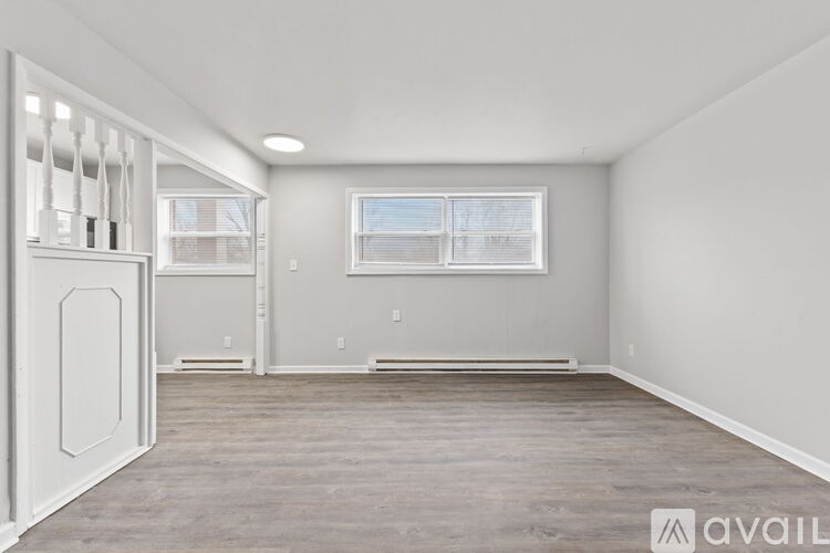 A spacious room with a window and wooden flooring.