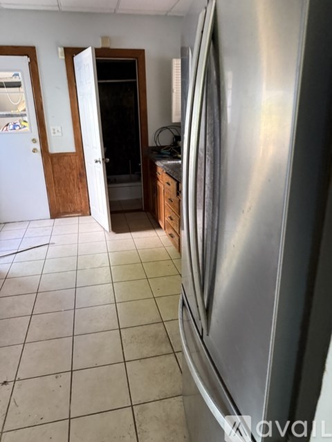 A kitchen with a stainless steel refrigerator and a tile floor.