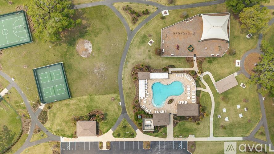 A bird's eye view of a residential area with a swimming pool and tennis courts.