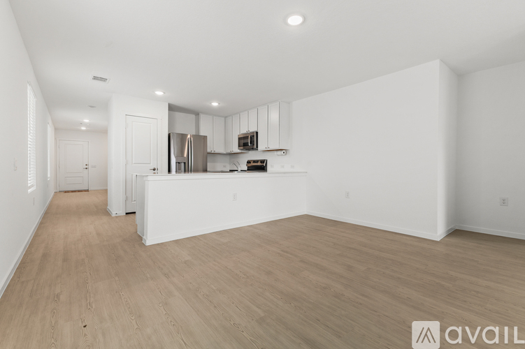 A spacious kitchen with white cabinets and a wooden floor.