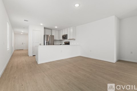 A spacious kitchen with white cabinets and a wooden floor.