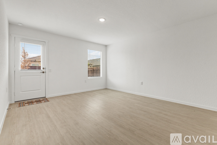 A room with a door and a window, with a wooden floor and white walls.