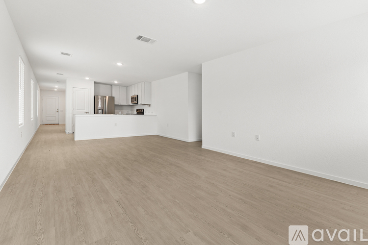 A spacious, empty room with light wood flooring and white walls.