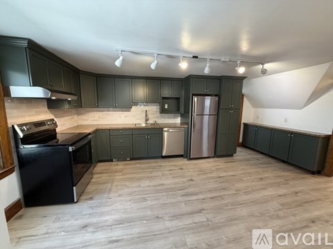 A kitchen with dark wood cabinets and a black fridge.