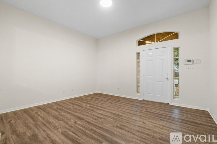 A room with a white door and wooden flooring.