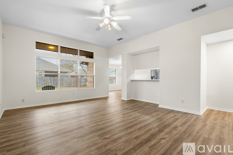 A spacious room with wooden flooring and a ceiling fan.