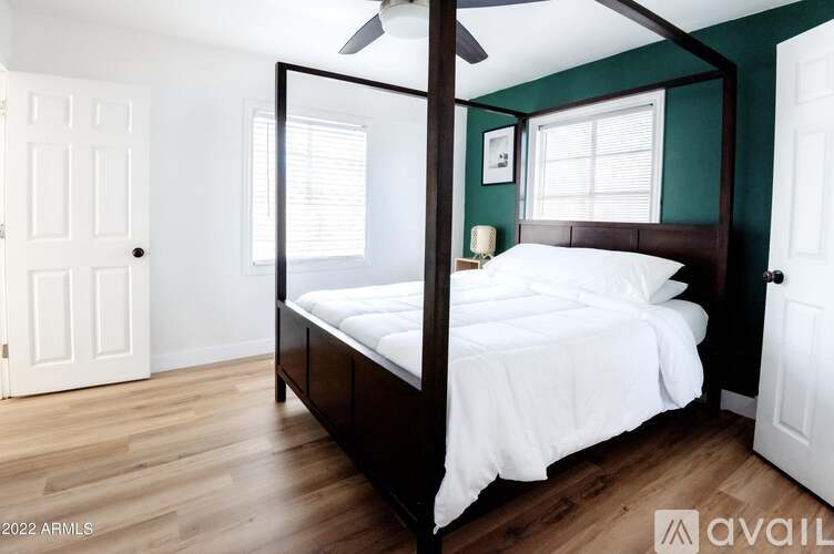 A bedroom with a four poster bed and a ceiling fan.