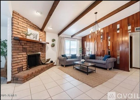 A living room with a brick fireplace and a grey couch.
