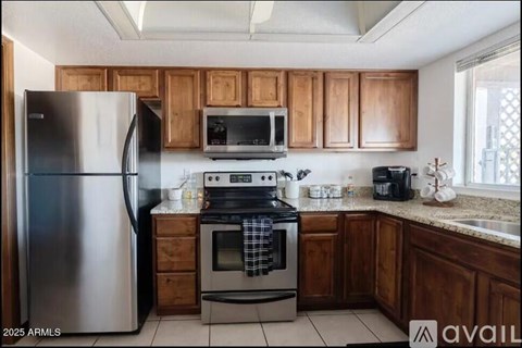 A kitchen with wooden cabinets and a stainless steel refrigerator.