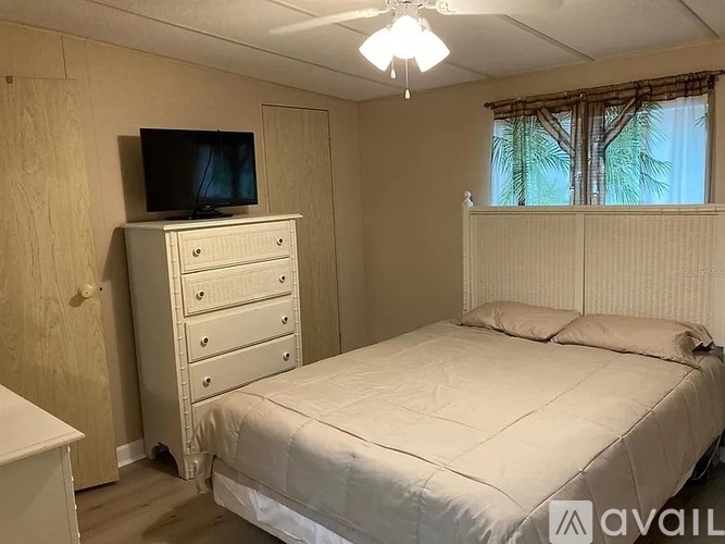 A bedroom with a bed, dresser, and a television.