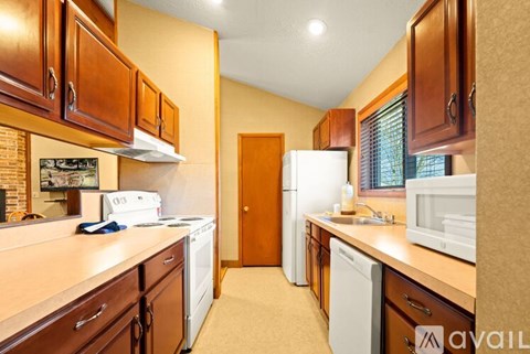 A kitchen with brown cabinets and a white refrigerator.