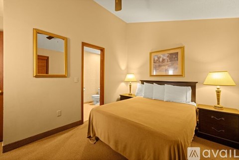 A bedroom with a bed, two lamps, and a framed picture on the wall.