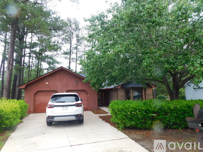 A white car is parked in front of a red garage.