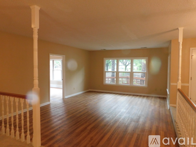 A spacious room with wooden floors and white columns.