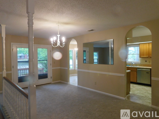A living room with a chandelier, a staircase, and a kitchen area.
