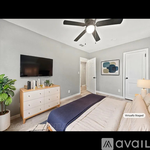 A bedroom with a bed, dresser, and ceiling fan.