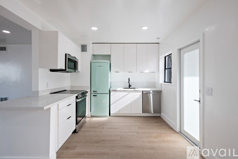 A kitchen with white cabinets and a green fridge.