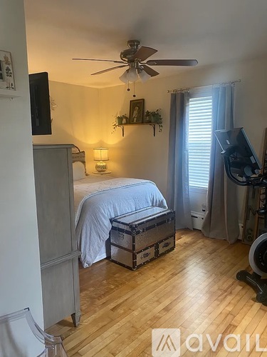 A bedroom with a bed, a ceiling fan, and a window with curtains.