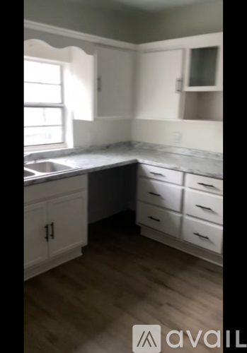 A kitchen with white cabinets and a wooden floor.