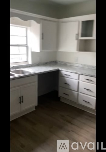 A kitchen with white cabinets and a wooden floor.