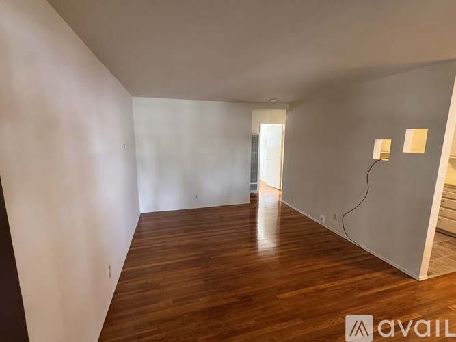 A room with wooden flooring and white walls is available for rent.