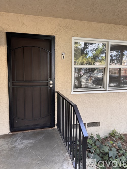 A black door is on the left and a window with a view of a tree is on the right.