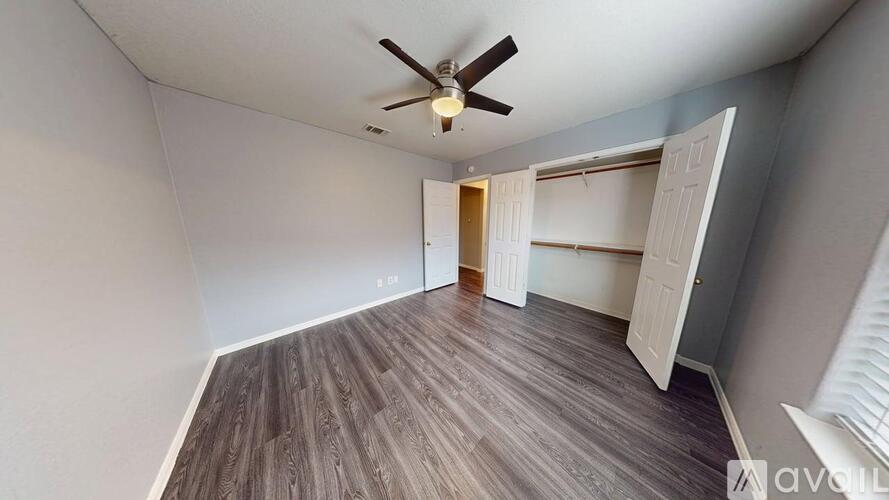 A room with a ceiling fan and wooden flooring.