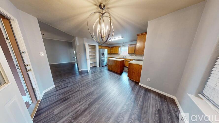 A large open space with wooden floors and a chandelier hanging from the ceiling.