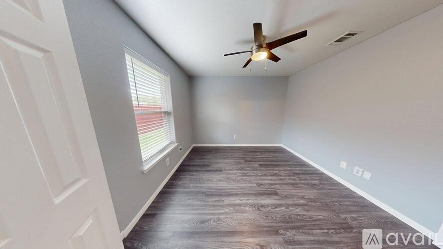 A room with a ceiling fan and wooden flooring.