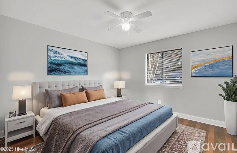 A bedroom with a large bed and two framed pictures on the wall.