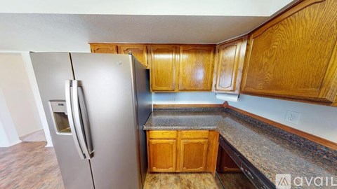 A kitchen with wooden cabinets and a stainless steel refrigerator.