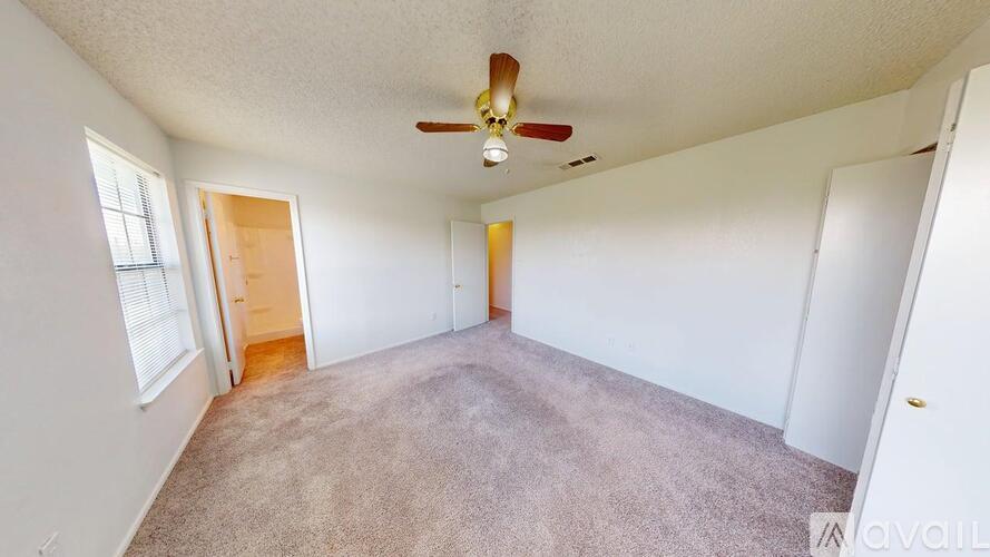 A spacious room with a ceiling fan and carpeted floor.