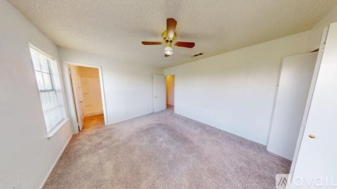 A spacious room with a ceiling fan and carpeted floor.