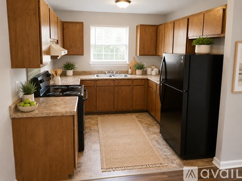 A kitchen with wooden cabinets and a black refrigerator.