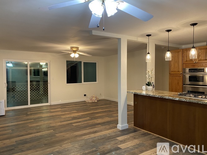 A kitchen with a ceiling fan and pendant lights.