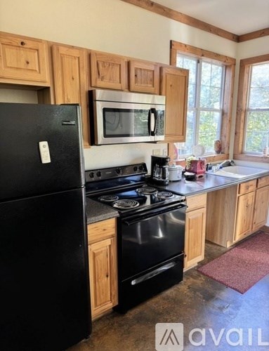 A kitchen with black appliances and wooden cabinets.