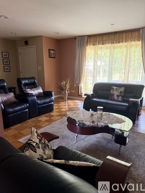 A living room with a black leather couch and a glass coffee table.