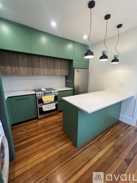 A kitchen with green cabinets and a wooden floor.