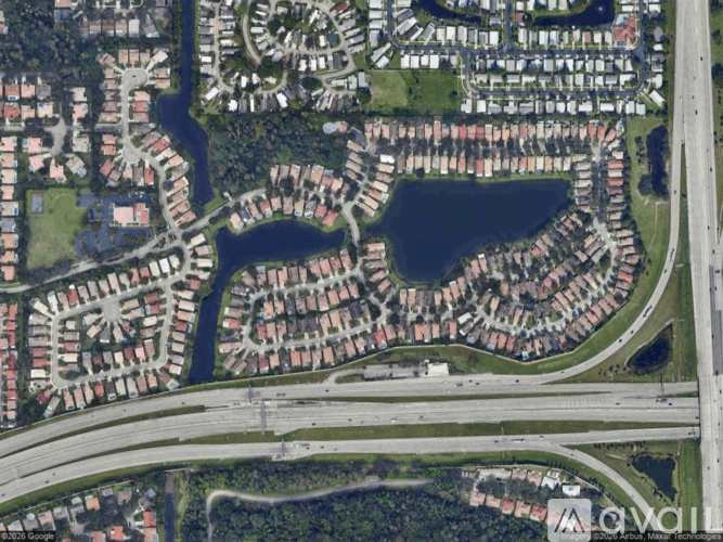 A satellite image of a residential area with a lake and a highway.
