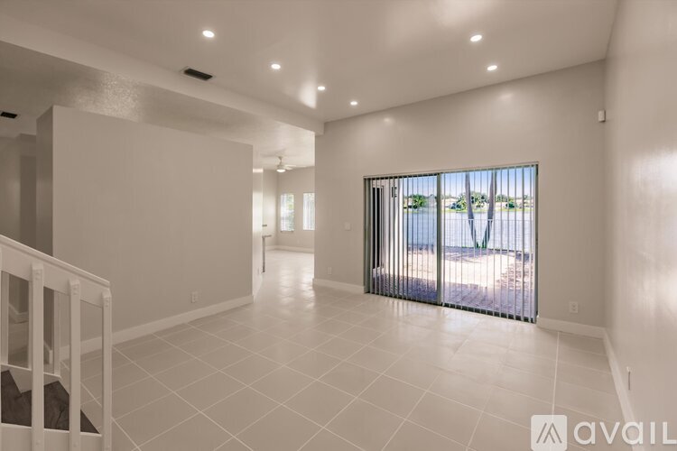 A spacious living room with a view of the outdoors through a sliding glass door.
