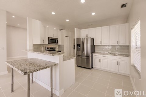 A kitchen with white cabinets and a granite table.