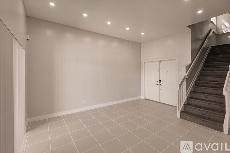 A spacious room with a staircase and a white door.
