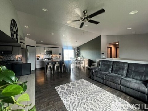 A modern living room with a grey sofa and a patterned rug.