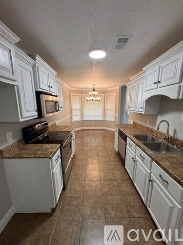 A kitchen with white cabinets and brown countertops.
