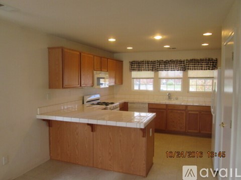 A kitchen with wooden cabinets and a checkered curtain.