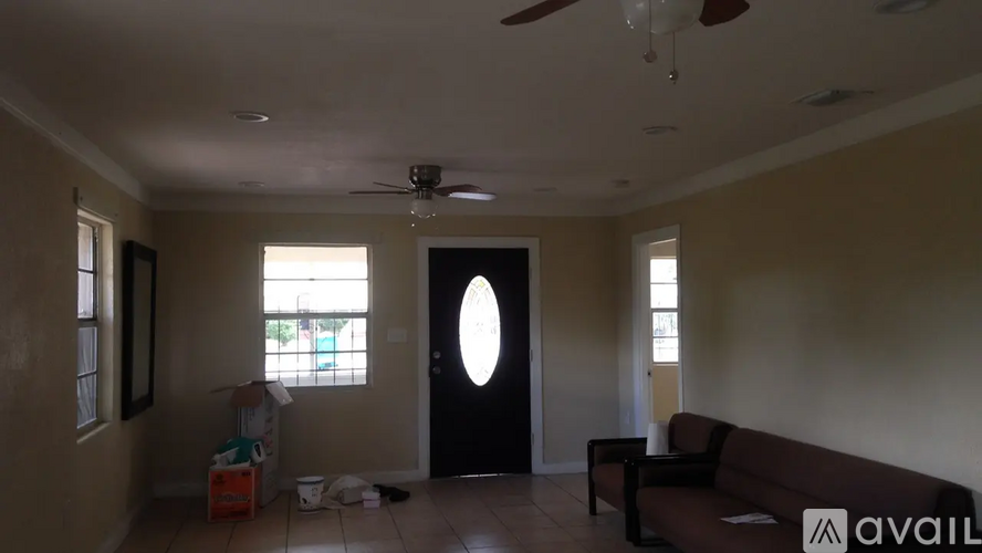 A living room with a couch, a chair, and a fan.