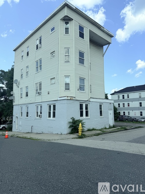 A white two-story building with a grey roof and a yellow fire hydrant in front.