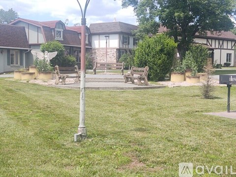 A grassy area with a bench and a lamp post in the foreground and a building in the background.