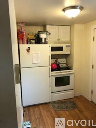 A kitchen with a white refrigerator and white cabinets.
