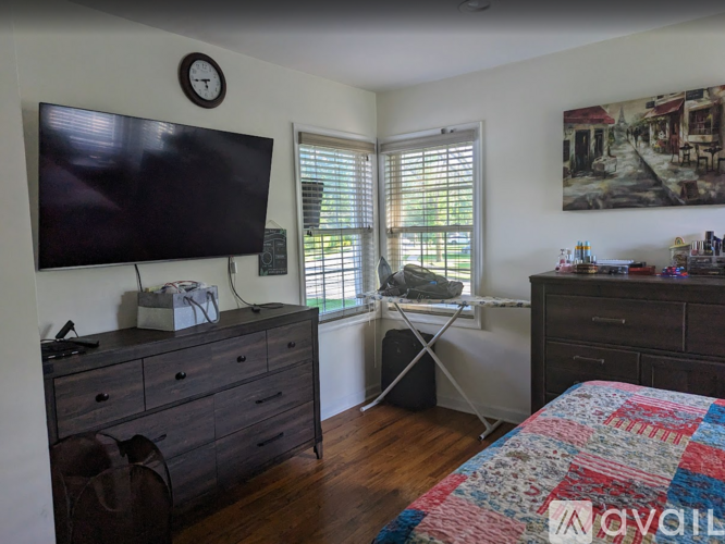 A bedroom with a bed, dresser, and a television.